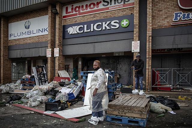 In a looted S. African mall, a man lies dead as the poor pick over scraps